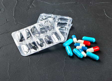 Scattered multicolored capsules with blister on a dark backgroundの写真素材