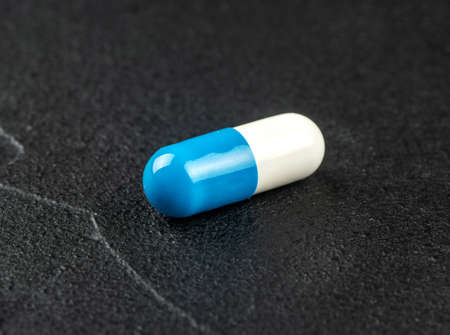 Blue white capsule on dark concrete backgroundの写真素材