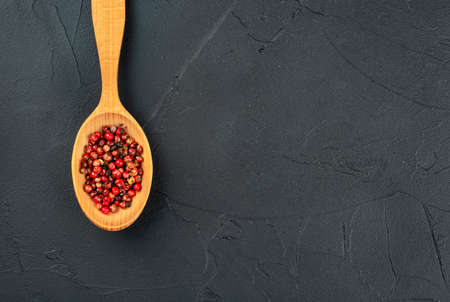 Red pepper peas in a wooden spoon on a concrete background closeupの写真素材