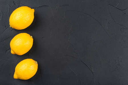 Three fresh lemon fruit on dark concrete background, top viewの写真素材