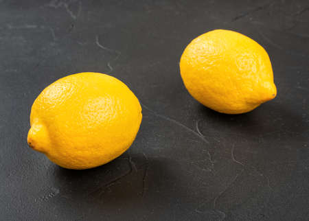 Two fresh lemon fruit on a dark concrete backgroundの写真素材