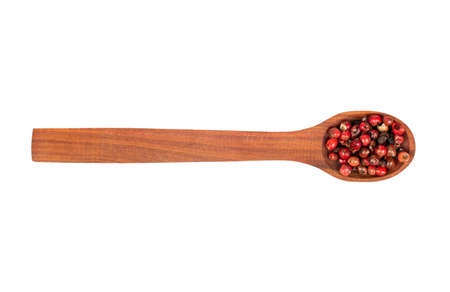 Red pepper peas in a wooden spoon on a white background, top view