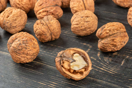 Scattered walnuts in shell closeup on wooden background