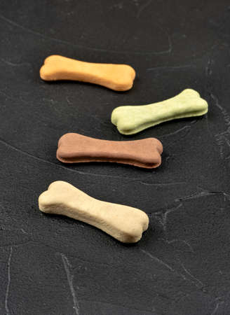 Four bone-shaped dog biscuits on a dark backgroundの写真素材
