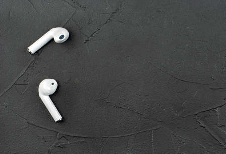 White wireless headphones on dark concrete background, top viewの写真素材