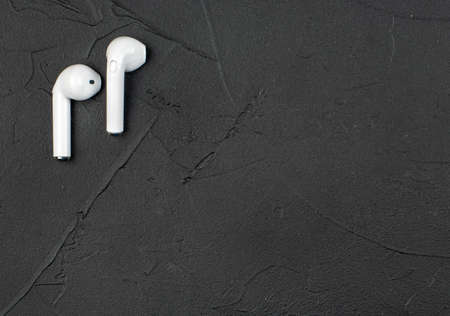 White wireless headphones on dark concrete background, top viewの写真素材