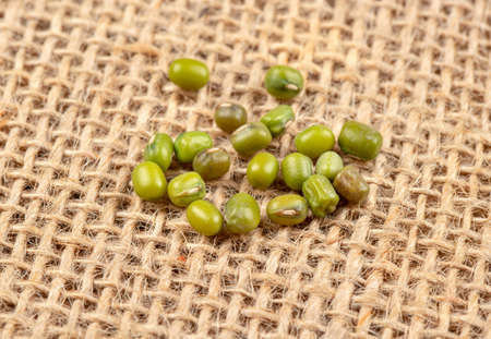 Raw green machine grains scattered on burlapの写真素材