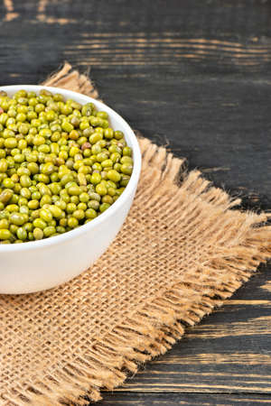 Part of a bowl of mung beans on a burlap close-up on the tableの写真素材