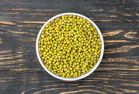 Bowl with raw green mung beans on a wooden background, top viewの写真素材