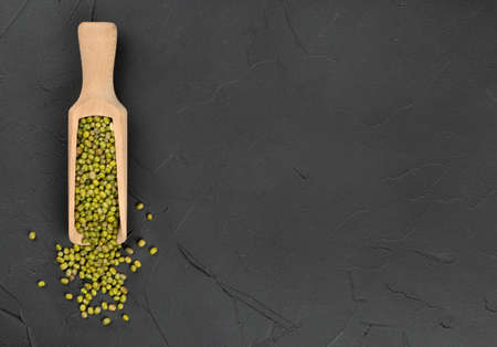Wooden scoop with green mung beans on concrete background, top viewの写真素材
