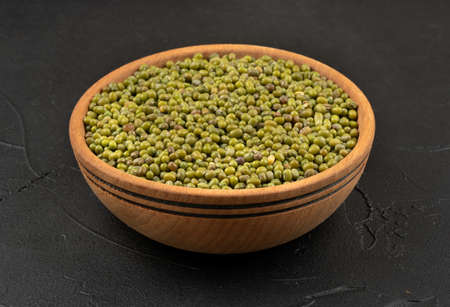 Large wooden bowl with mung beans on dark backgroundの写真素材