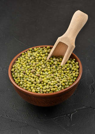 Mung beans in a bowl with a wooden scoop on a concrete backgroundの写真素材