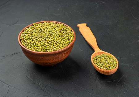 Raw mung beans in bowl and spoon on dark concrete backgroundの写真素材