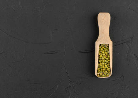 Wooden scoop with green mung beans on concrete background, top viewの写真素材