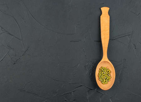 Wooden spoon with green mung beans on empty concrete background, top viewの写真素材