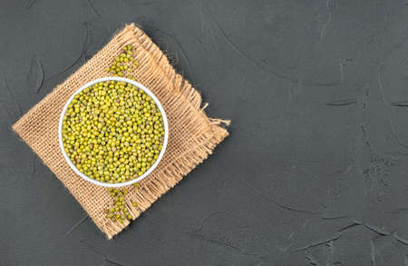 Raw mung bean in a bowl on a burlap on an empty concrete backgroundの写真素材