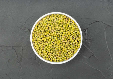 White ceramic bowl with raw mung grains on concrete background, top viewの写真素材