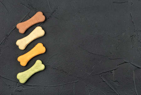 Four bone shaped dog biscuits on a dark background, top viewの写真素材