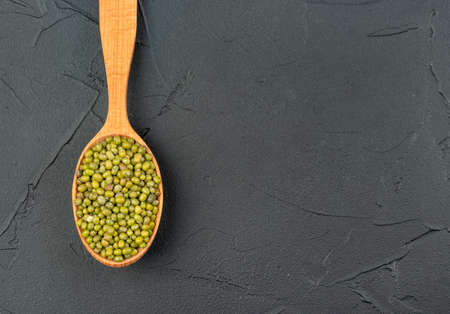 Grains of green mash in a wooden spoon on a dark backgroundの写真素材