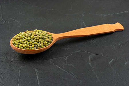Large wooden spoon with green mung grains on concrete backgroundの写真素材