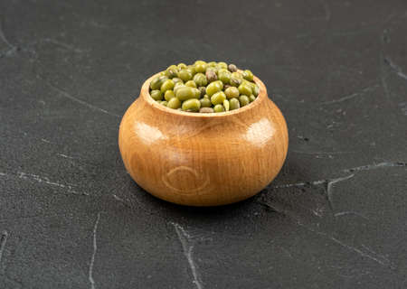 Green mung beans in a wooden container on a dark backgroundの写真素材