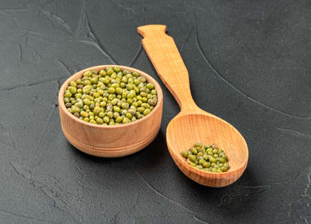 Green mung bean in spoon and bowl on dark backgroundの写真素材
