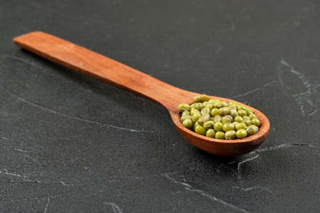 Wooden spoon with green mung beans on concrete backgroundの写真素材