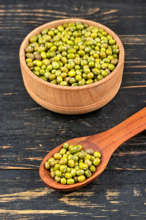 Green mung beans in bowl and spoon on wooden backgroundの写真素材