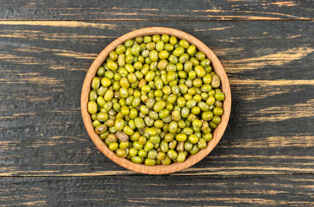 Bowl with raw green mung beans on a wooden background, top viewの写真素材