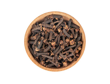 Dry cloves in wooden bowl isolated on white background, top viewの写真素材