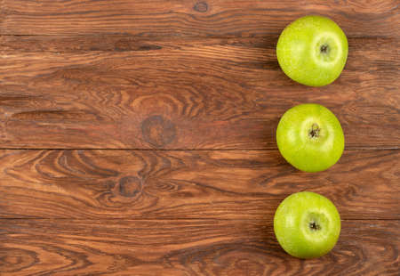 Three ripe green apples on a wooden background, top viewの写真素材