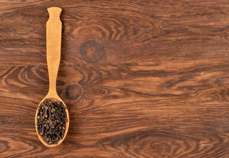 Spoon with dry cloves on wooden background, top viewの写真素材