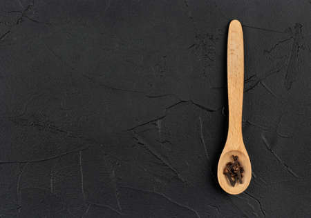 Dry cloves in a small wooden spoon on a dark background, top viewの写真素材