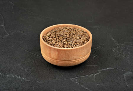 Dry cumin in a wooden bowl on a dark concrete backgroundの写真素材