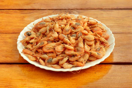 Small cooked shrimp in a white bowl on the tableの写真素材