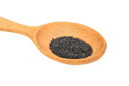 Black sesame seeds in large wooden spoon close up on white backgroundの写真素材