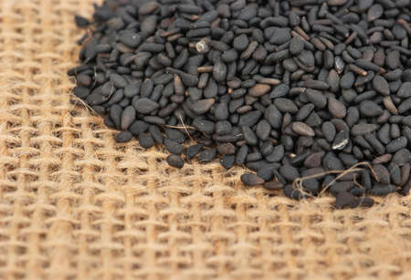Scattered black sesame seeds close-up on burlapの写真素材