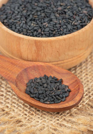 Black sesame seeds in spoon and bowl close up on burlapの写真素材
