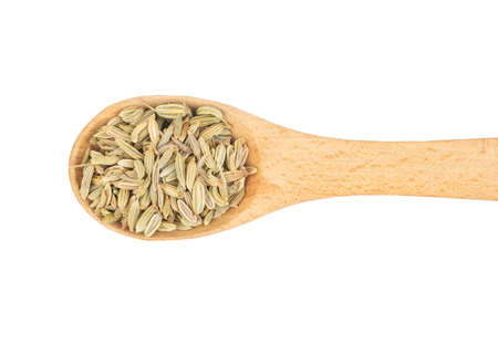 Dry fennel grains in wooden spoon on white background, top viewの写真素材