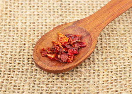 Pieces of dry red pepper in a wooden spoon on burlapの写真素材