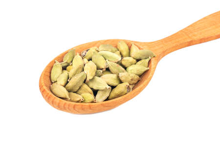 Dry cardamom in a large wooden spoon on a white background closeupの写真素材
