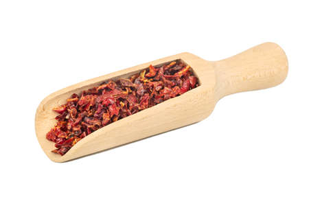 Pieces of dry red pepper in a wooden scoop on a white backgroundの写真素材