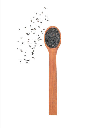 Wooden spoon with scattered black sesame seeds on a white backgroundの写真素材
