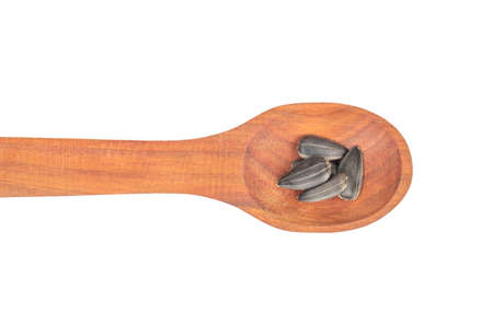 Sunflower seeds in a small wooden spoon on a white background, top viewの写真素材