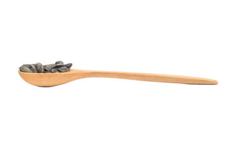 Sunflower seeds in a small wooden spoon on a white backgroundの写真素材