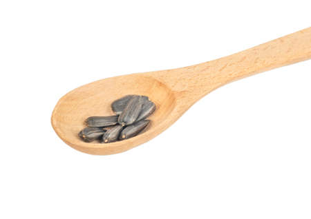 Sunflower seeds in a small wooden spoon on a white background closeupの写真素材