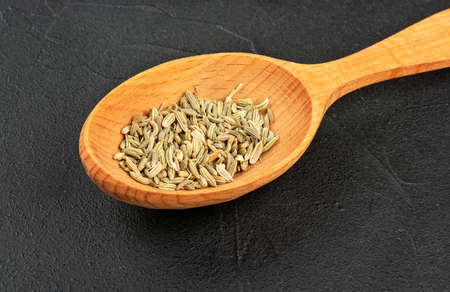 Dry fennel in spoon close up on dark backgroundの写真素材