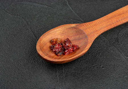 Small spoon with dry barberry on dark background closeupの写真素材