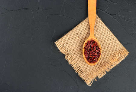 Dry barberry in wooden spoon on burlap and dark backgroundの写真素材