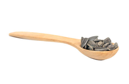Sunflower seeds in a small wooden spoon on a white backgroundの写真素材